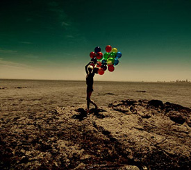 Девушка бежит по степи со связкой воздушных шаров с гелием