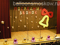 сцена концертного зала украшена латексными и фольгированными шарами к последнему звонку